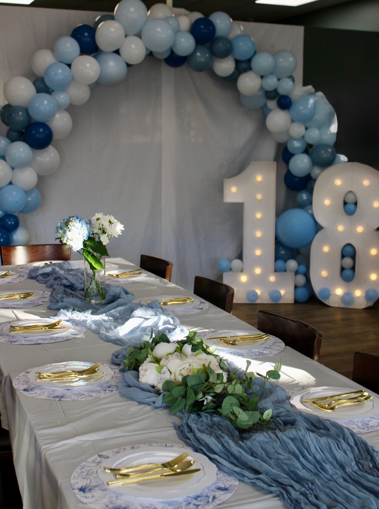 Blue-themed celebration with balloon arch and marquee number display.