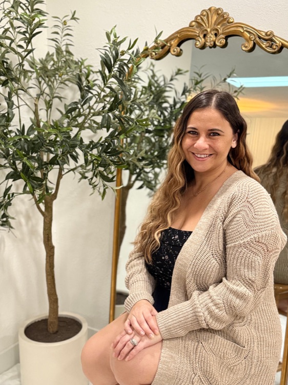 Alexa Gault, founder of Knot Your Average Event Co, seated beside an olive tree.