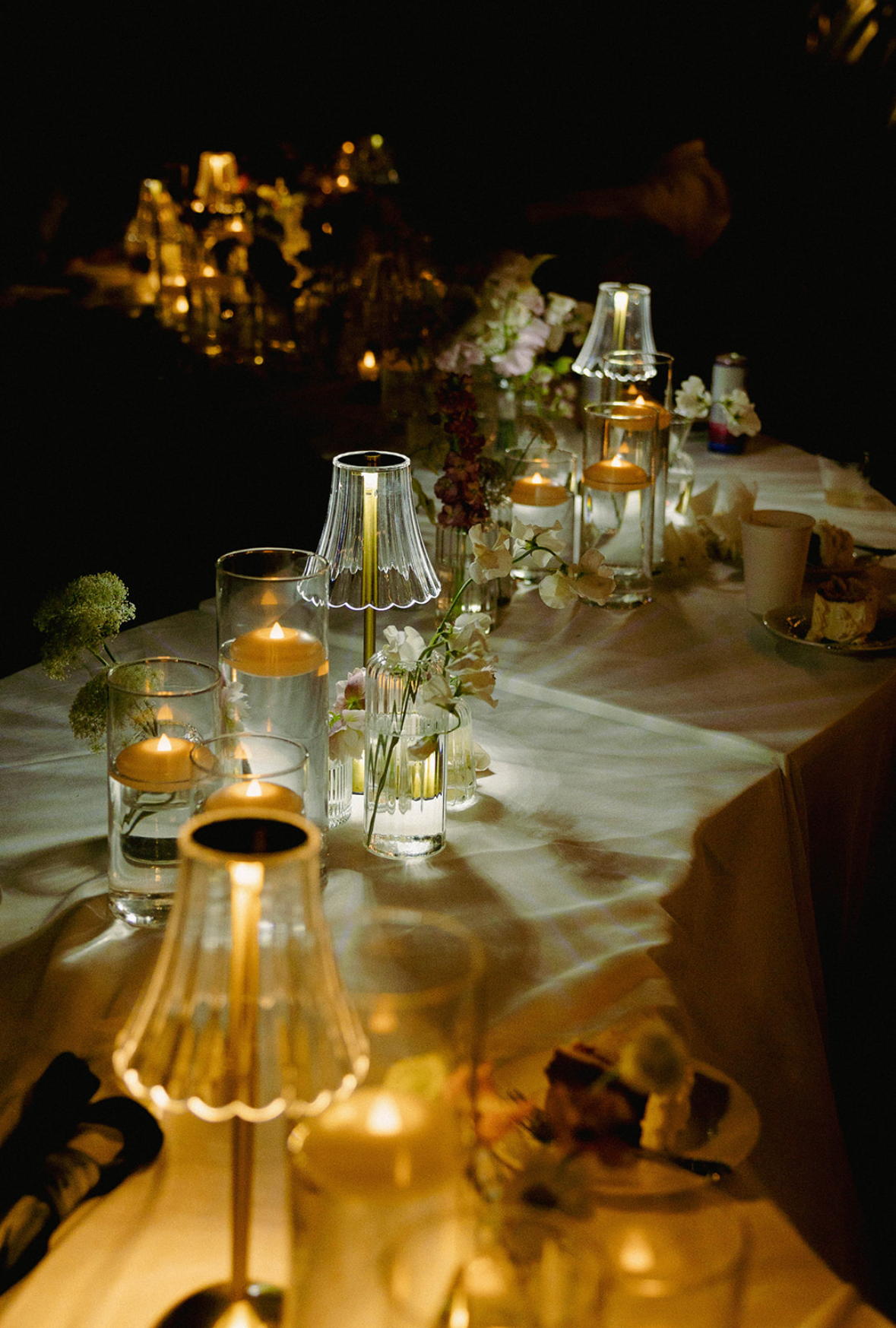 Candlelit dinner table with glassware and floral arrangements.